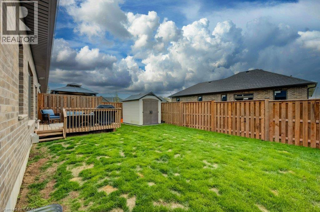 Rear exterior featuring a wood deck, manicured lawn, and privacy fencing - 15 Matheson Crescent, Innerkip, ON - Outdoor With Deck Patio Veranda