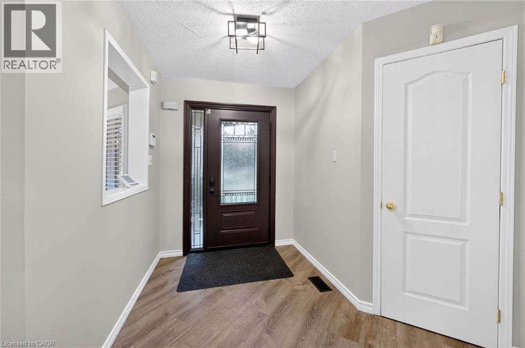 Foyer featuring a dark wood-finish entry door with decorative glass, wood-finish flooring, and light gray wall paint - 43 Liam Drive, Ancaster, ON - Indoor Photo Showing Other Room