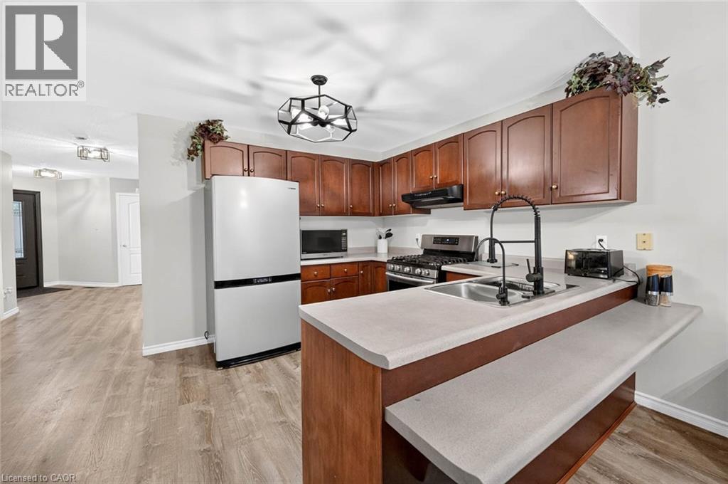 Kitchen featuring wood-finish cabinetry, light-toned countertops, and a black gooseneck faucet - 43 Liam Drive, Ancaster, ON - Indoor Photo Showing Kitchen