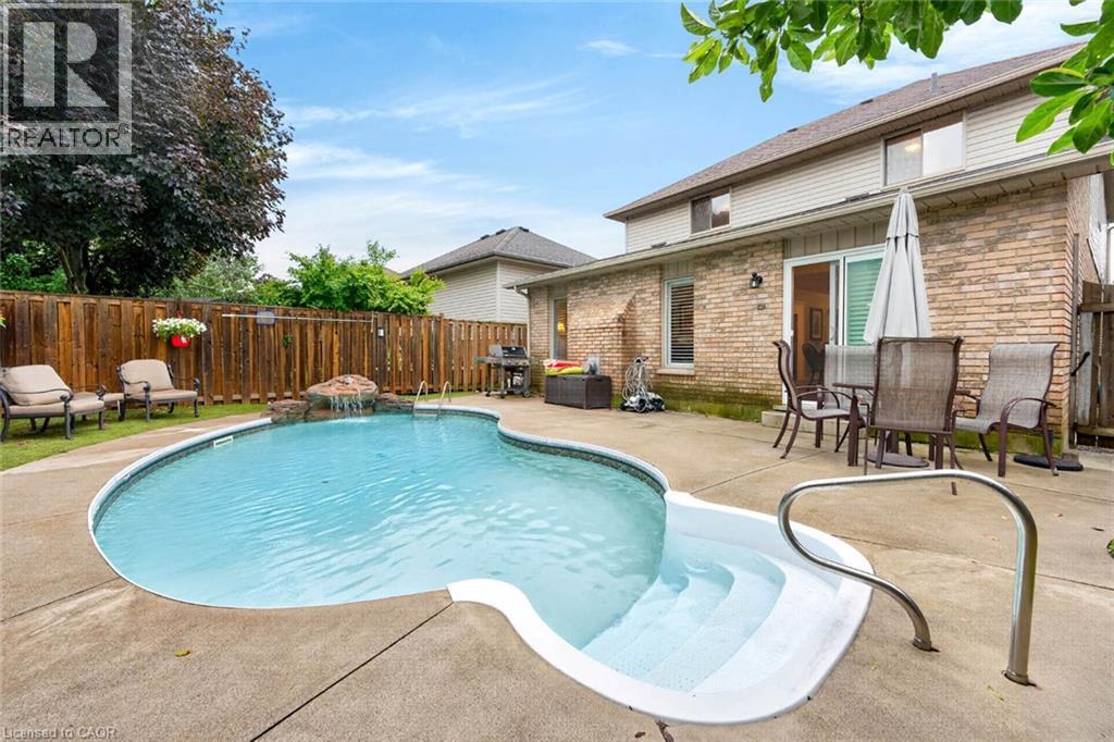 Backyard oasis featuring an in-ground pool with integrated steps, a rock waterfall feature, and a privacy fence - 43 Liam Drive, Ancaster, ON - Outdoor With In Ground Pool With Deck Patio Veranda