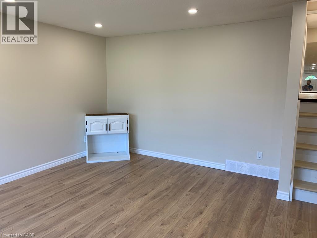 Light wood-finish flooring complements neutral wall tones - 86 Belwood Crescent, Kitchener, ON - Indoor Photo Showing Other Room
