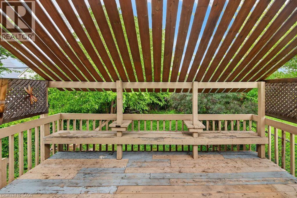Outdoor deck featuring a slatted wood pergola, built-in benches, and wood railing - 23 Harrison Avenue, Hamilton, ON - Outdoor With Deck Patio Veranda