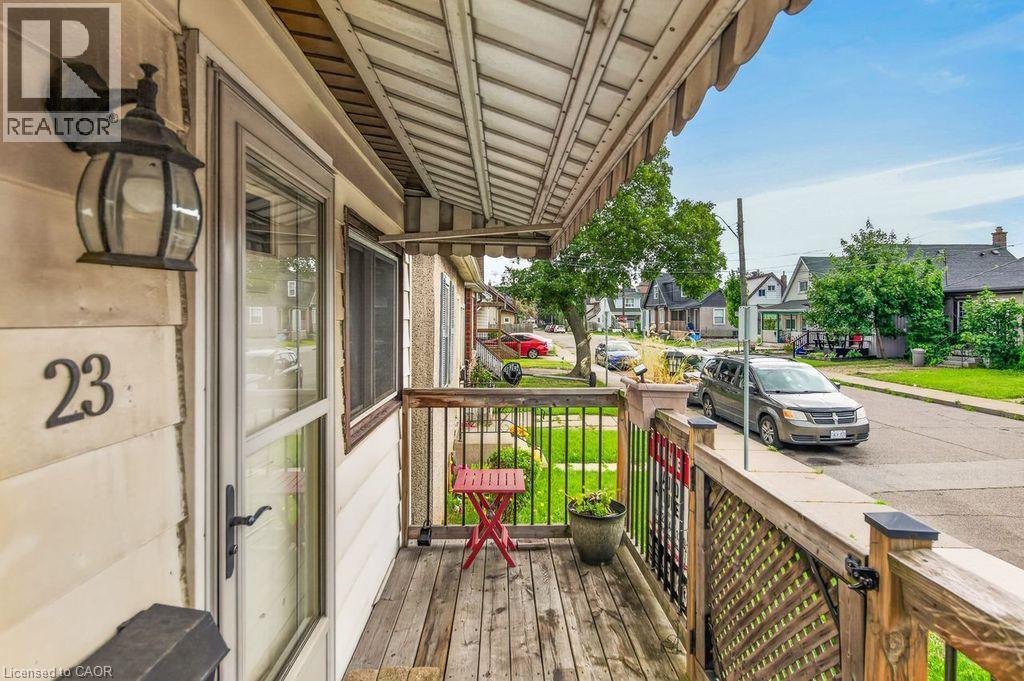 Front porch with wood decking, lattice railing, and an overhead awning - 23 Harrison Avenue, Hamilton, ON - Outdoor With Exterior