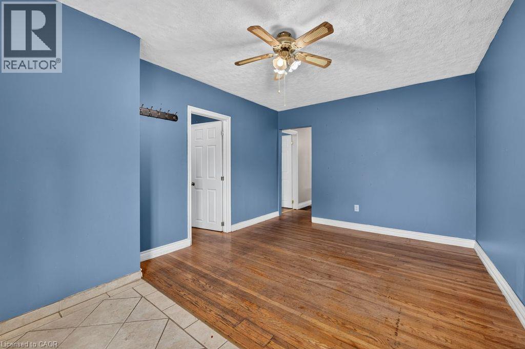 Room featuring wood-finish flooring, light blue walls, white trim, and a ceiling fan with integrated lighting - 23 Harrison Avenue, Hamilton, ON - Indoor Photo Showing Other Room