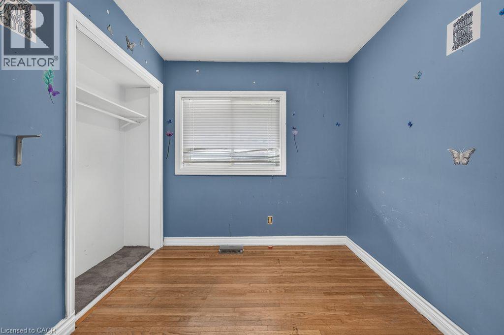 Room featuring wood-finish flooring, a window with blinds, and an open closet with shelving - 23 Harrison Avenue, Hamilton, ON - Indoor Photo Showing Other Room