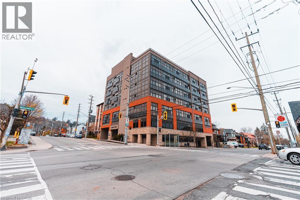 Modern building with a multi-textured facade including stone, orange-toned paneling, and dark-framed windows - 427 Aberdeen Avenue Unit# 102, Hamilton, ON - Outdoor