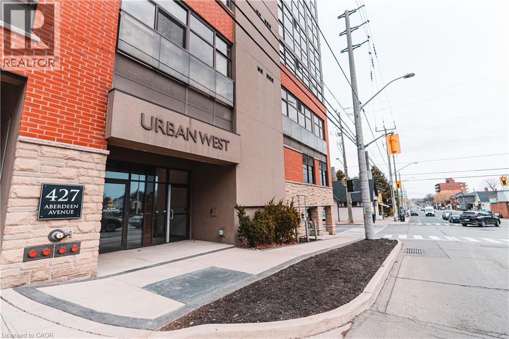 Modern building entrance featuring a prominent ""URBAN WEST"" sign, glass double doors, and stone veneer accents - 427 Aberdeen Avenue Unit# 102, Hamilton, ON - Outdoor