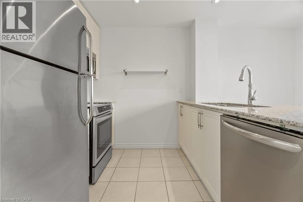 Modern kitchen featuring stainless steel appliances, granite countertops, a stainless steel sink with a gooseneck faucet, white cabinetry with silver hardware, and tile flooring - 427 Aberdeen Avenue Unit# 102, Hamilton, ON - Indoor Photo Showing Kitchen