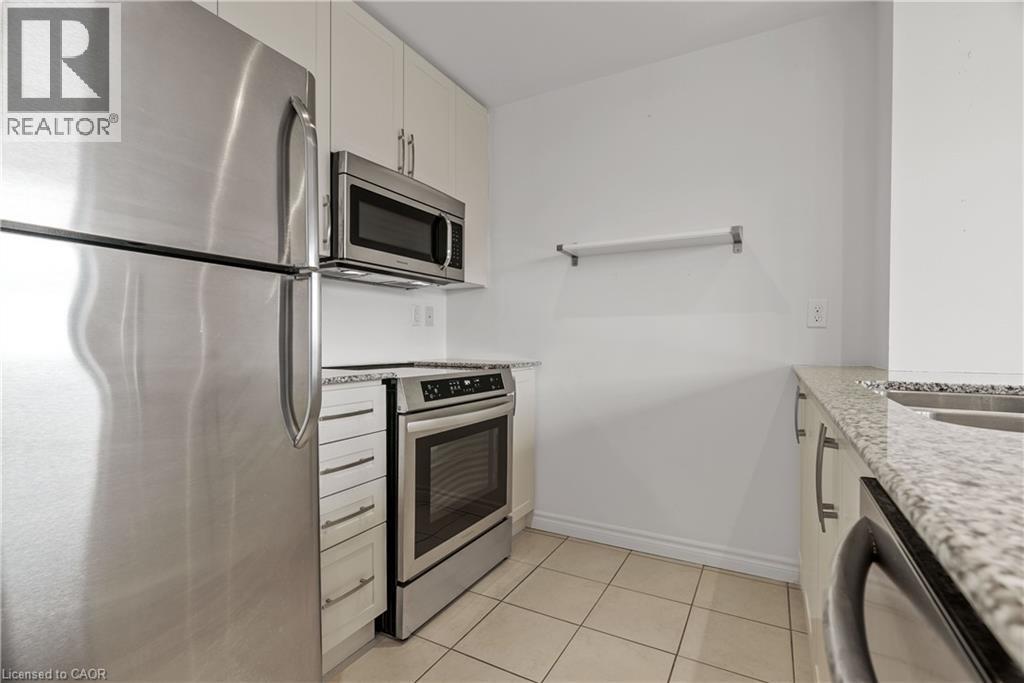 Compact kitchen featuring stainless steel appliances, speckled stone countertops, and white cabinetry - 427 Aberdeen Avenue Unit# 102, Hamilton, ON - Indoor Photo Showing Kitchen