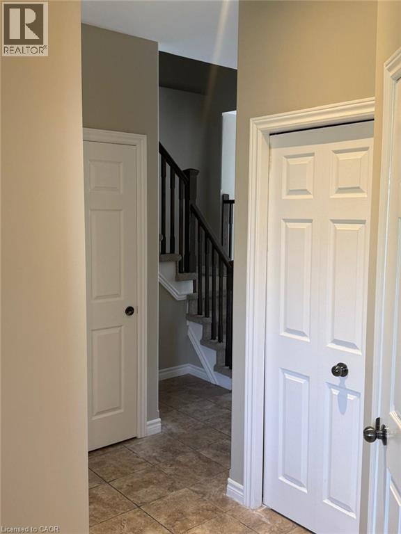 Staircase featuring dark wood balusters and a carpeted tread, complemented by light brown wall paint and tiled flooring - Upper-313 Featherstone Crescent, Kitchener, ON - Indoor Photo Showing Other Room