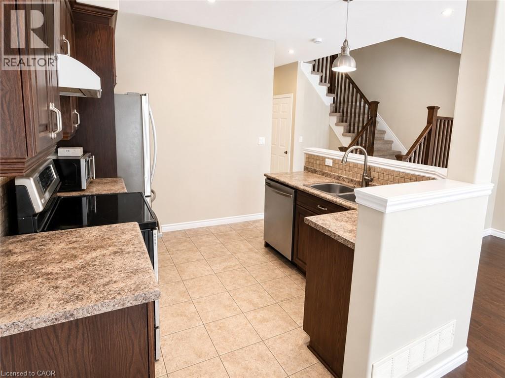 Kitchen featuring dark wood-finish cabinetry, stainless steel appliances, and stone-look countertops - Upper-313 Featherstone Crescent, Kitchener, ON - Indoor Photo Showing Kitchen With Double Sink