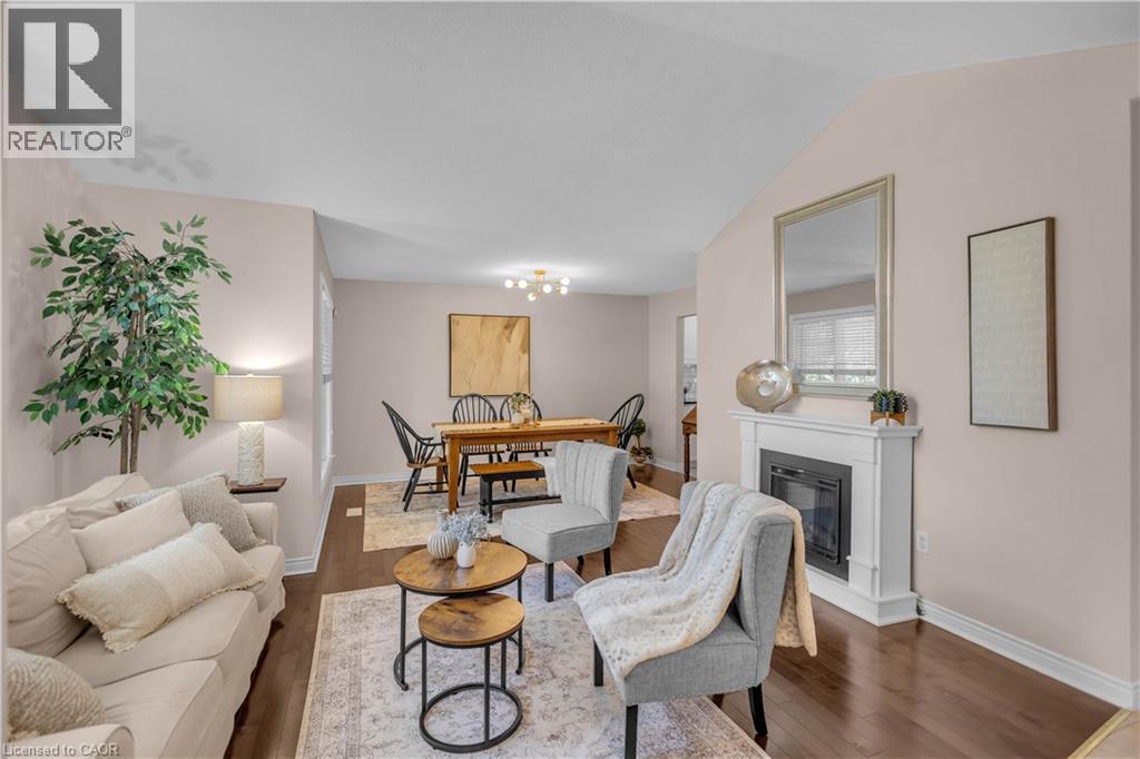 Living area featuring wood-finish flooring, a white mantel fireplace, and vaulted ceilings - 65 Thistlemoor Drive, Caledonia, ON - Indoor Photo Showing Living Room With Fireplace
