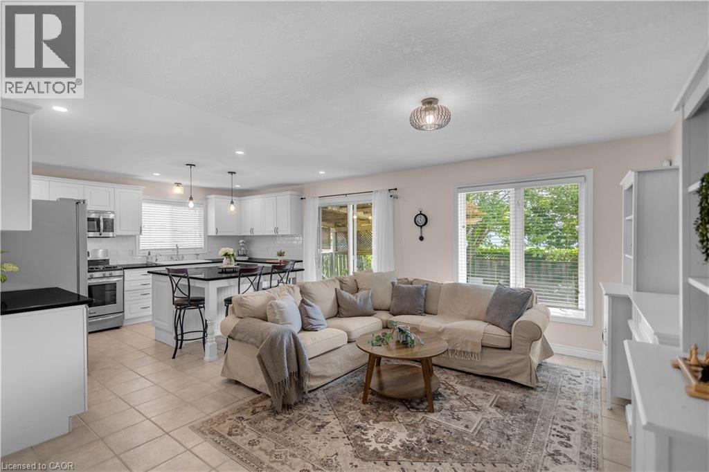 Open concept living area featuring a kitchen with white cabinetry, a dark countertop island, and stainless steel appliances - 65 Thistlemoor Drive, Caledonia, ON - Indoor