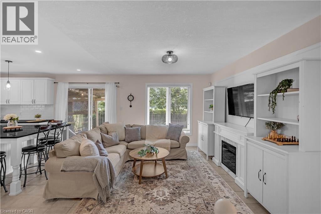 Open-concept living space featuring a built-in entertainment center with an electric fireplace, white cabinetry, and recessed lighting - 65 Thistlemoor Drive, Caledonia, ON - Indoor Photo Showing Living Room With Fireplace
