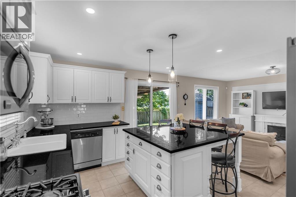 Modern kitchen featuring white cabinetry, black countertops, stainless steel appliances, and a central island with pendant lighting - 65 Thistlemoor Drive, Caledonia, ON - Indoor Photo Showing Kitchen With Upgraded Kitchen