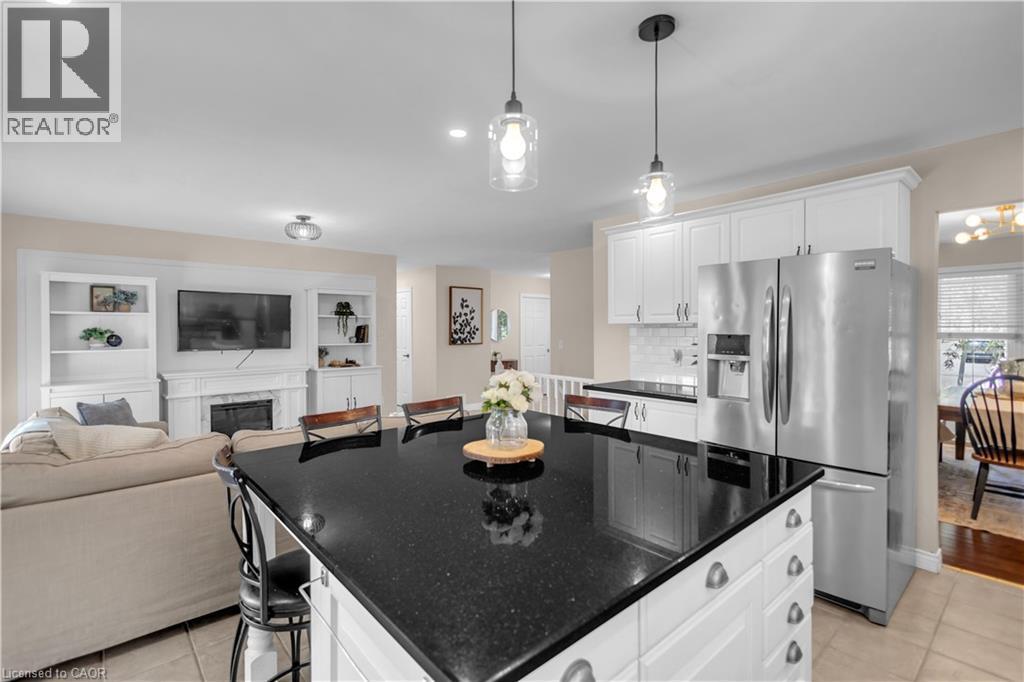 Kitchen island featuring a black countertop, white base cabinetry, and pendant lighting - 65 Thistlemoor Drive, Caledonia, ON - Indoor Photo Showing Kitchen With Upgraded Kitchen