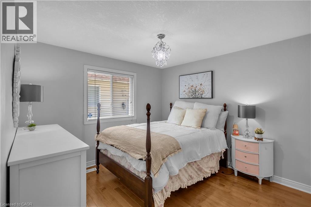 Hardwood-finish flooring featuring light gray painted walls and a crystal chandelier - 65 Thistlemoor Drive, Caledonia, ON - Indoor Photo Showing Bedroom