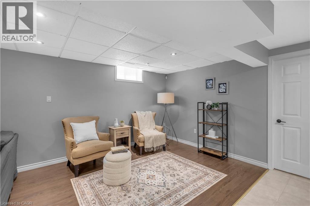 Finished room featuring wood-finish flooring, a drop ceiling with recessed lighting, painted walls, and a white interior door with black hardware - 65 Thistlemoor Drive, Caledonia, ON - Indoor