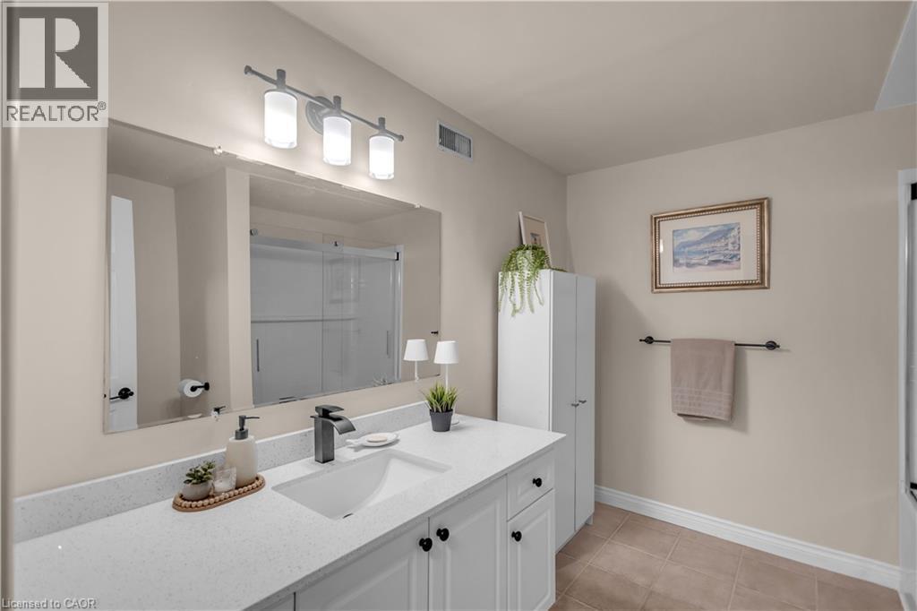 Bathroom featuring a large vanity with an integrated sink, a dark finish faucet, and a wall-mounted tri-light fixture - 65 Thistlemoor Drive, Caledonia, ON - Indoor Photo Showing Bathroom