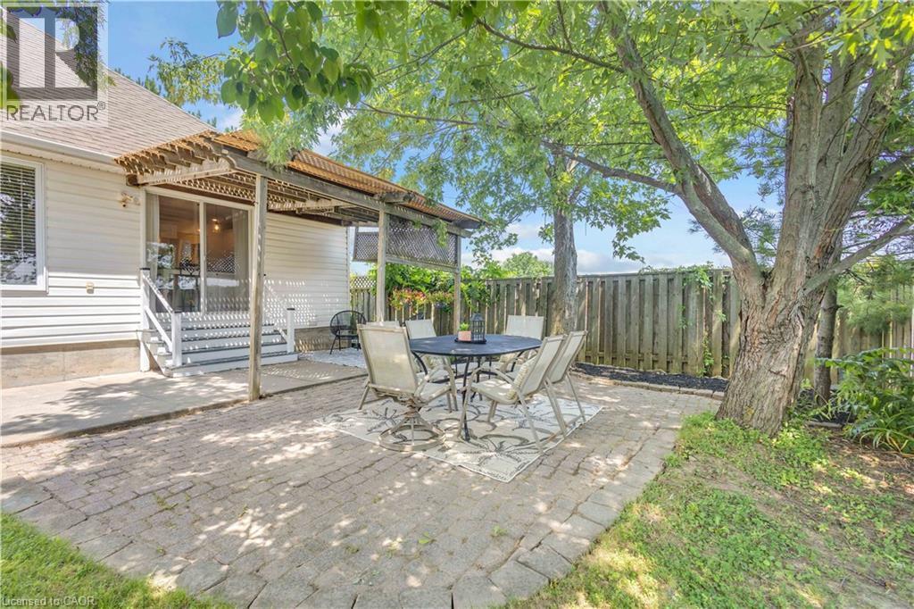 Outdoor patio featuring paver stone flooring, a wooden pergola, and mature trees providing natural shade - 65 Thistlemoor Drive, Caledonia, ON - Outdoor