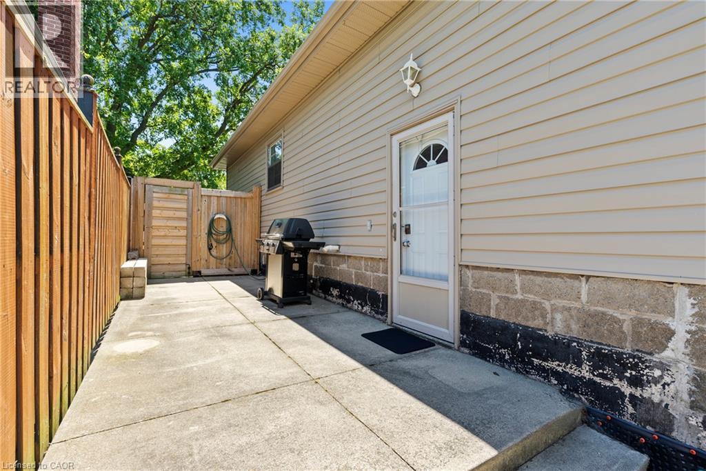 Concrete patio area with a privacy fence, wood gate, and exterior siding - 258 Sanatorium Road, Hamilton, ON - Outdoor With Exterior