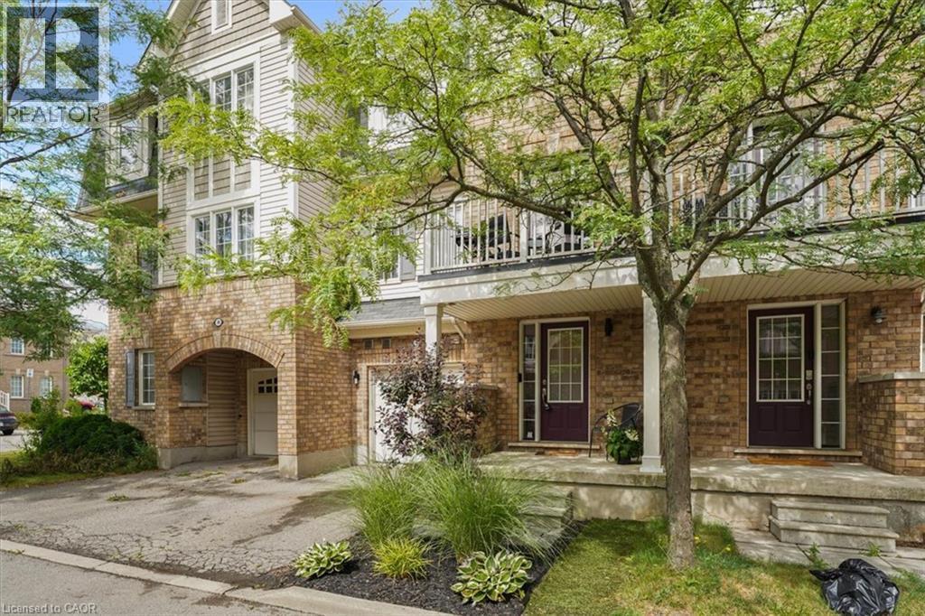 Multi-level townhouse exterior featuring brick and horizontal siding construction, multiple balconies with white railings, dark entry doors with glass inserts, and an integrated arched carport - 7 Sirente Drive Unit# 7, Hamilton, ON - Outdoor With Balcony