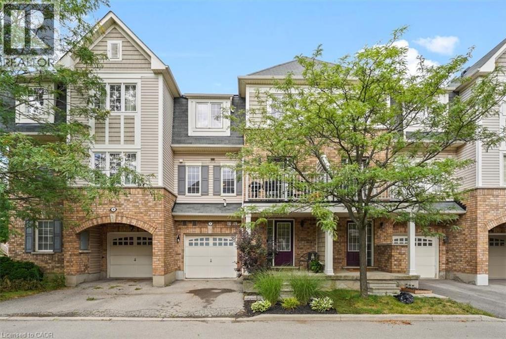 Multi-level townhome featuring brick and siding exterior, multiple gabled rooflines, a covered entry porch, and an arched garage entryway - 7 Sirente Drive Unit# 7, Hamilton, ON - Outdoor With Balcony With Facade