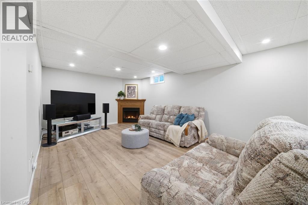 Spacious room featuring wood-finish flooring, a wood-surround fireplace, recessed ceiling lighting, and light gray wall finishes - 200 Morrison Drive, Caledonia, ON - Indoor Photo Showing Basement