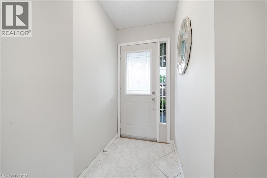 Entryway featuring a white door with decorative glass inserts, a full-length sidelight, and square tile flooring - 200 Morrison Drive, Caledonia, ON - Indoor Photo Showing Other Room