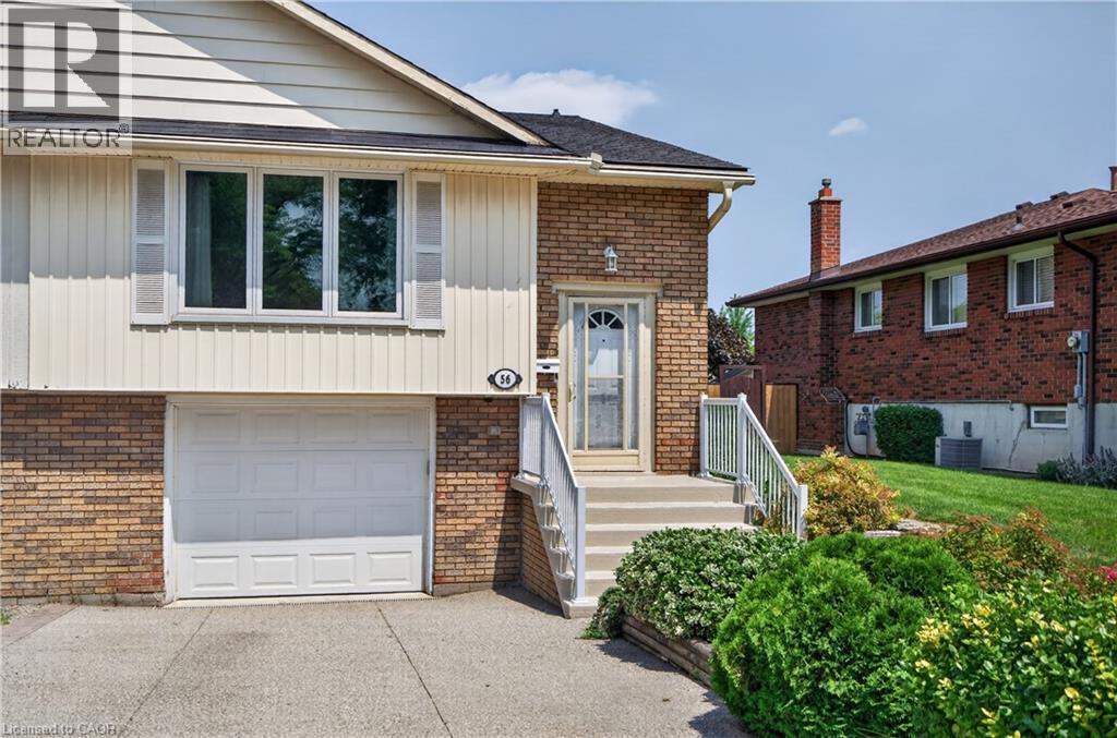 Brick and siding exterior featuring a white garage door, front entry with white storm door, and a concrete driveway - 56 Brookstream Court, Hamilton, ON - Outdoor With Exterior