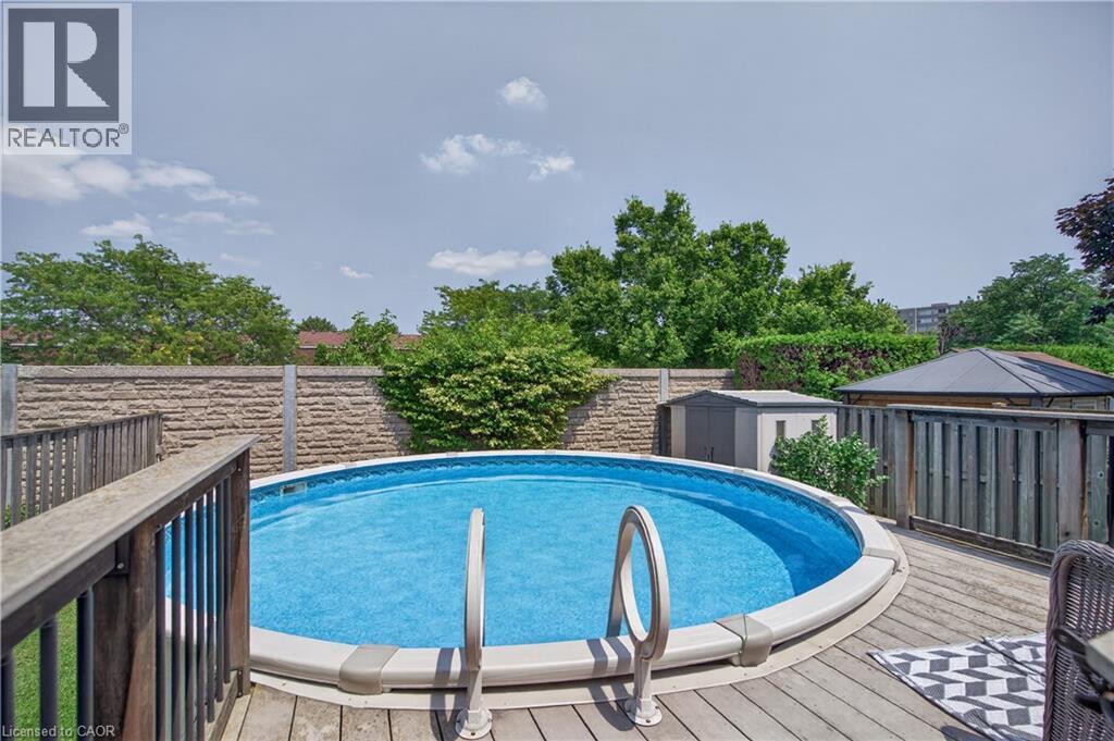 Expansive wooden deck surrounding a circular above-ground pool with integrated entry steps - 56 Brookstream Court, Hamilton, ON - Outdoor With Above Ground Pool With Deck Patio Veranda
