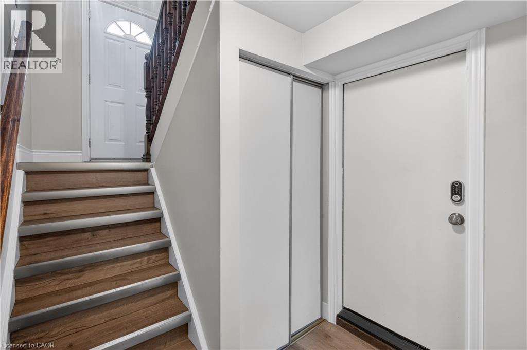 Entryway featuring wood-finish stairs with metal non-slip treads, a dark wood banister, and light gray wall paint - 56 Brookstream Court, Hamilton, ON - Indoor Photo Showing Other Room