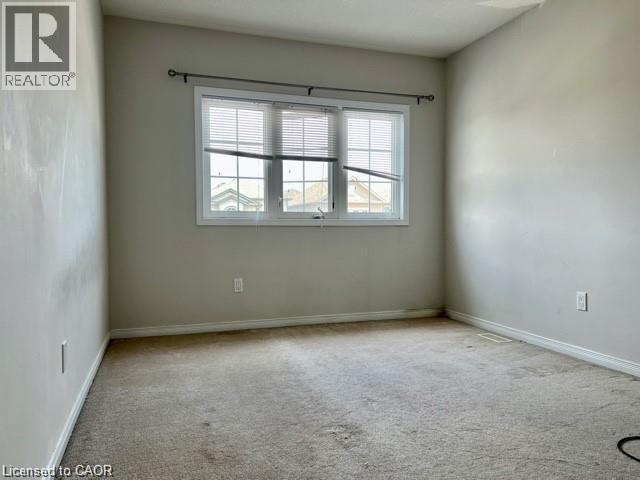 Neutral-toned room featuring a large window with white blinds and trim - 300 Countrystone Crescent, Kitchener, ON - Indoor Photo Showing Other Room
