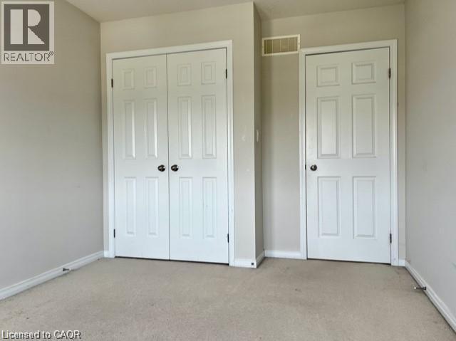 Neutral-toned room featuring a double bifold closet door, a single paneled door, and light beige carpet flooring - 300 Countrystone Crescent, Kitchener, ON - Indoor