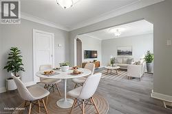 Open-concept living area featuring light gray walls, crown molding, and wood-finish flooring - 