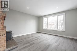 Room featuring wood-finish flooring, light grey walls, and a large window with white trim - 