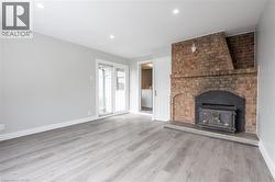 Expansive room featuring a brick fireplace with a wood-burning stove, light wood-finish flooring, and recessed ceiling lighting - 