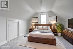 Sloped ceiling bedroom featuring a single window, white trim, and light gray wall paint - 
