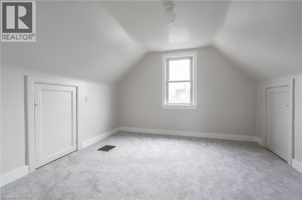 Attic room featuring a single window, two panel doors, sloped ceilings, and light gray carpeting - 156 Adeline Avenue, Hamilton, ON - Indoor Photo Showing Other Room
