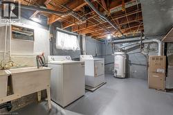 Laundry area featuring a double utility sink, exposed ceiling joists, and concrete walls - 