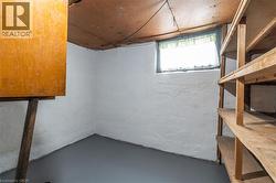 Basement area featuring a painted concrete floor, white painted walls, a single window, built-in wooden shelving, and an overhead wood-paneled ceiling - 
