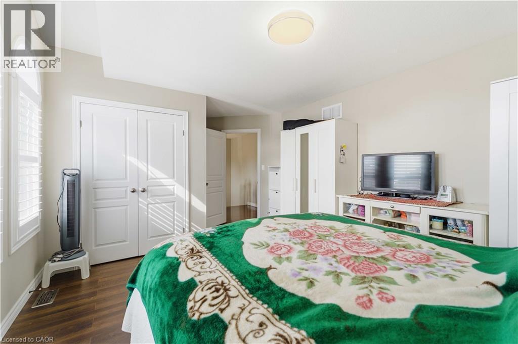 Room featuring wood-finish flooring, an arched window with louvered shutters, and a ceiling-mounted light fixture - 212 Chartwell Circle, Hamilton, ON - Indoor Photo Showing Bedroom