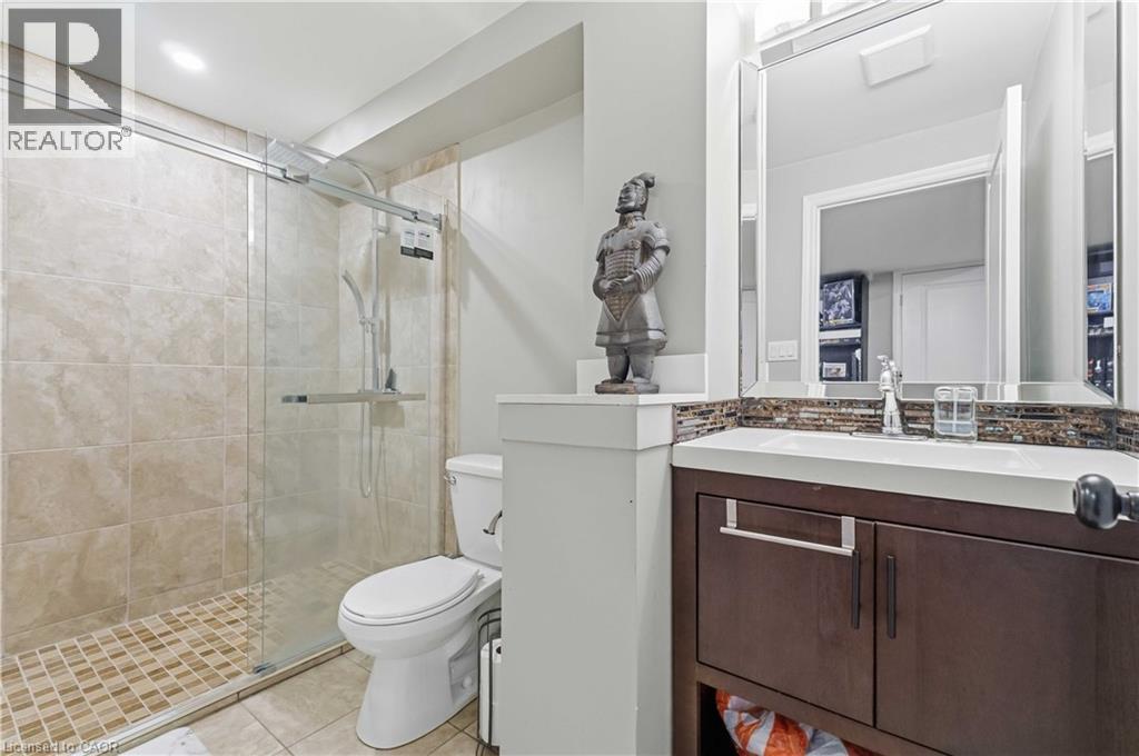 Bathroom featuring a glass-enclosed shower with tile surround, a dark wood-finish vanity with an integrated sink, a mosaic tile backsplash, and a framed mirror - 212 Chartwell Circle, Hamilton, ON - Indoor Photo Showing Bathroom