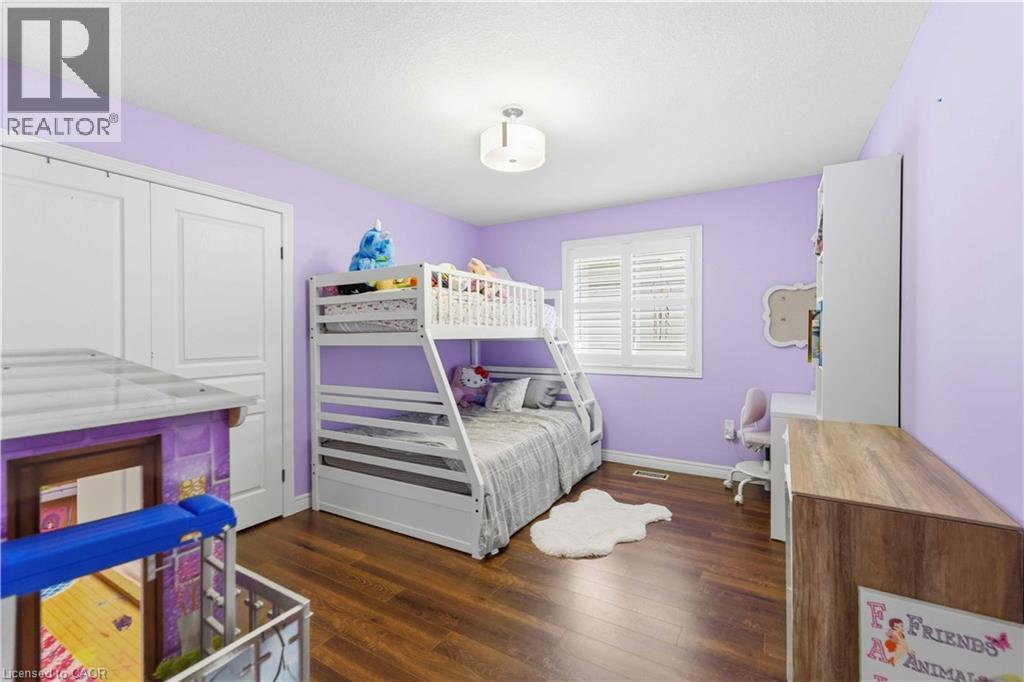 Hardwood-finish flooring featuring a window with white louvered shutters, ceiling-mounted light fixture, and white bi-fold closet doors - 212 Chartwell Circle, Hamilton, ON - Indoor Photo Showing Bedroom