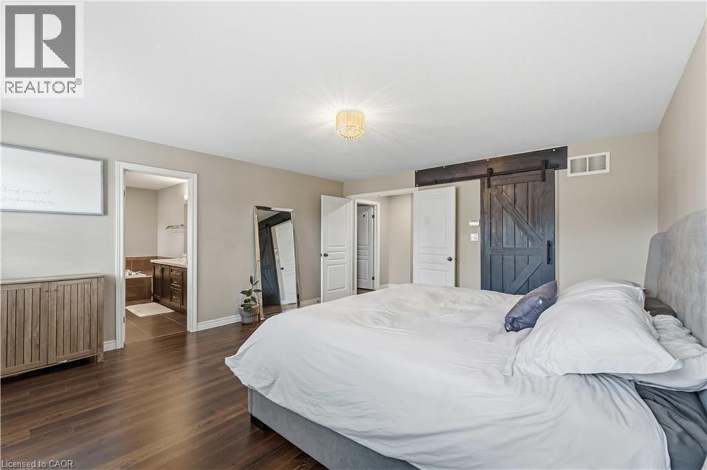 Spacious room featuring wood-finish flooring, a contemporary ceiling light fixture, and neutral wall tones - 212 Chartwell Circle, Hamilton, ON - Indoor Photo Showing Bedroom