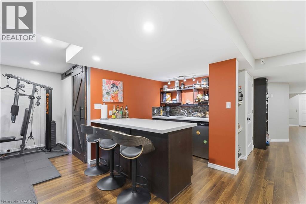 Entertainment area featuring a wet bar with a light countertop, dark wood-finish cabinetry, and a dark tile backsplash - 212 Chartwell Circle, Hamilton, ON - Indoor