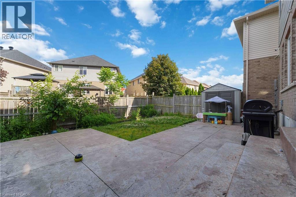 Expansive backyard featuring a concrete patio, a privacy fence, a storage shed, and mature trees - 212 Chartwell Circle, Hamilton, ON - Outdoor