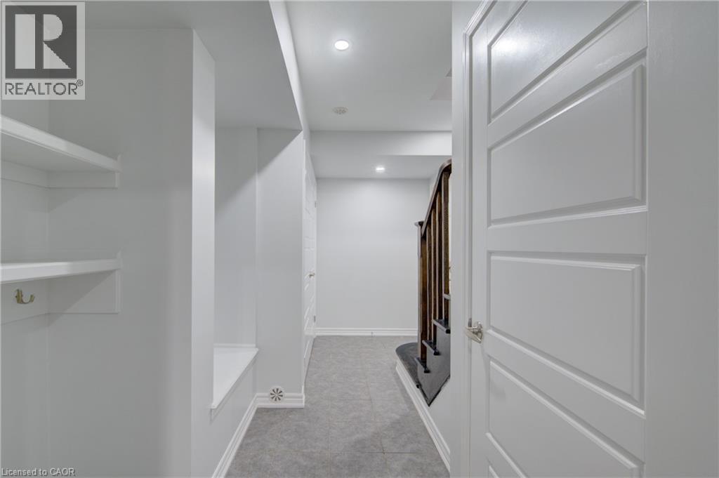 Hallway with recessed lighting, built-in shelving, panel doors, and a wood-finish staircase - 911 Apple Hill Lane, Kitchener, ON - Indoor Photo Showing Other Room