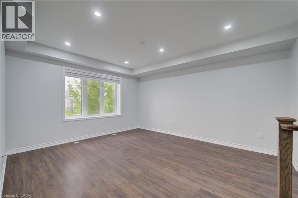 Spacious interior with wood-finish flooring, recessed lighting, and a large multi-pane window - 911 Apple Hill Lane, Kitchener, ON - Indoor Photo Showing Other Room