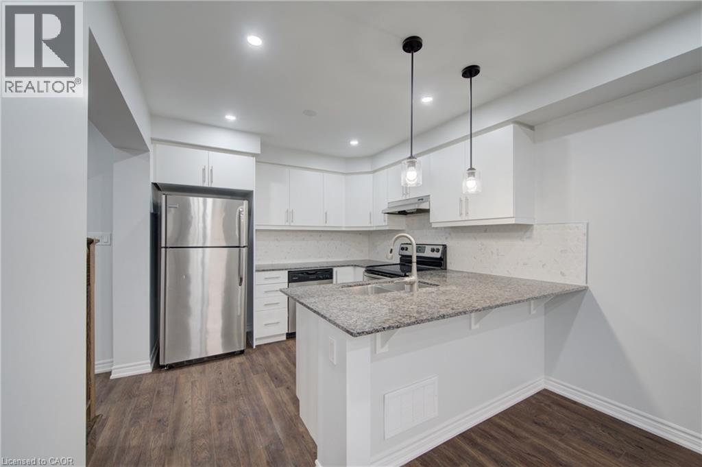 Modern kitchen featuring white cabinetry, stainless steel appliances, granite countertops, and wood-finish flooring - 911 Apple Hill Lane, Kitchener, ON - Indoor Photo Showing Kitchen With Stainless Steel Kitchen With Upgraded Kitchen